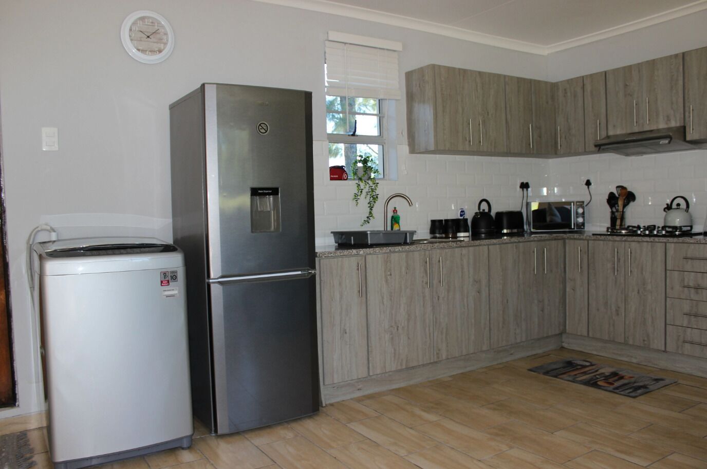 Eine Küche mit einem Edelstahl-Kühlschrank, einer Mikrowelle und Holzschränken.
