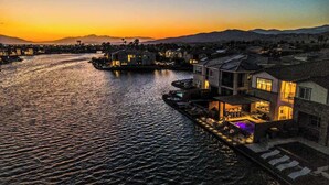 A waterfront property with a pool, outdoor seating, and a view of the water. - Bali Hai Villa on the Lake (Indio)