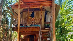 Eine rustikale Holzkonstruktion mit Wellblechdach, einer Holztreppe und einem Balkon.