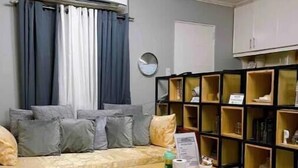 Una habitación con sofá, mesa de centro, estantería y aire acondicionado.
