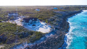Vista aérea de una propiedad costera con una casa grande, piscina y costa rocosa.
