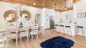 Una cocina moderna con armarios blancos, una isla central con taburetes y un techo de madera.
