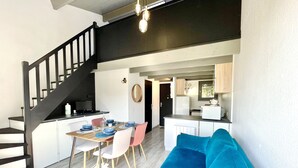 Ein modernes Interieur mit Treppe, Essbereich, Küche und einem blauen Sofa.