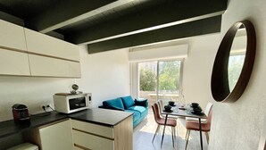 Eine kompakte Küche mit Mikrowelle, Kaffeemaschine und einem Essbereich mit Tisch und Stühlen.