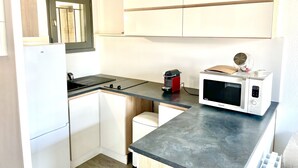 Eine kleine Küche mit Kühlschrank, Mikrowelle und Spüle.