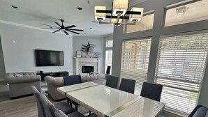 A modern living room with a dining table, sofas, a fireplace, and a TV.