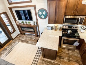 Une cuisine compacte avec des meubles en bois, un four à micro-ondes encastré, une cuisinière et un grille-pain.