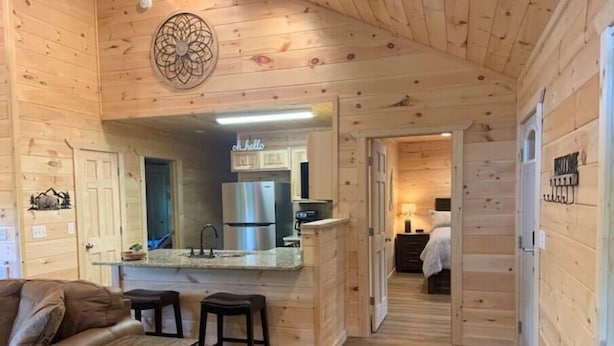 Een knus vakantiehuisje met een kitchenette, een eethoek met tafel en stoelen, en een slaapkamer met een bed.