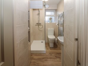 A narrow bathroom with a shower, toilet, and sink. - 8 Market Place (Ripon)
