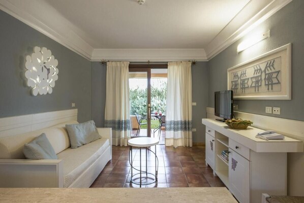 A modern living room with a sofa, a dining table, and a kitchen area with a TV. - Tranquil Lantana Resort Hotel & Apartments 1 Bedroom Room Apartment Sleeps 5 per (Pula)