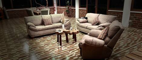 A spacious living room with two sofas, a coffee table, and a brick wall.