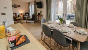 Un coin repas avec une table dressée pour quatre personnes, des chaises et un assortiment de produits pour le petit-déjeuner, notamment des croissants et du jus de fruits.