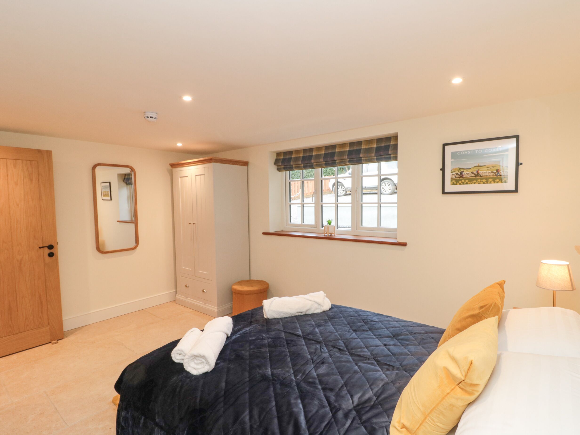 A bedroom with a bed, a wardrobe, a window with a view, a mirror, and a picture on the wall.