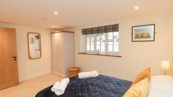 A bedroom with a bed, a wardrobe, a window with a view, a mirror, and a picture on the wall.