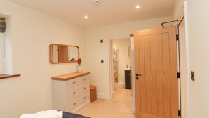 Une chambre à coucher avec un lit, une commode, un miroir et une porte en bois.