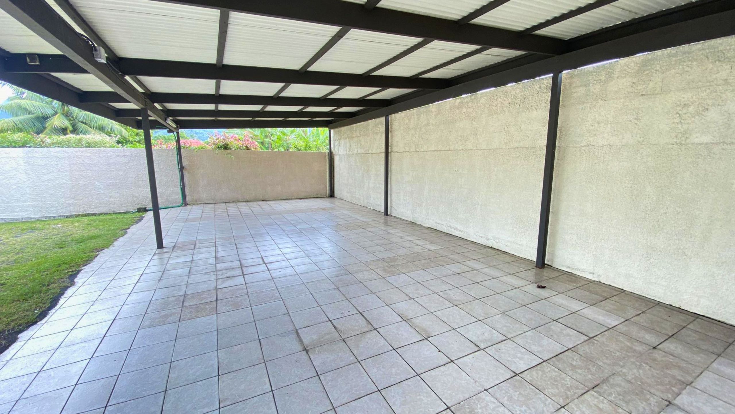 Ein überdachter Patio-Bereich mit Fliesenböden und einer Betonwand.
