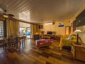 Una habitación con una mesa de comedor, sillas, un sofá, un televisor y una lámpara.