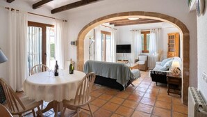 A cozy room with a bed, a TV, and a dining area with chairs and a table. - Belle Villa Avec Piscine 5 x 10 m, Grand Jardin Privatif, Proche des Plages (JAVEA)