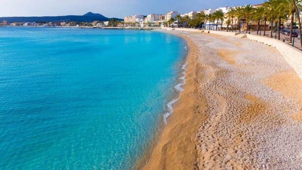 A coastal beach with clear turquoise waters, a sandy shoreline, and a promenade lined with palm trees. - Belle Villa Avec Piscine 5 x 10 m, Grand Jardin Privatif, Proche des Plages (JAVEA)