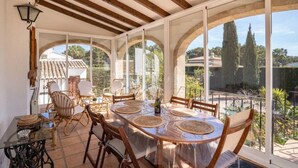 A sunlit patio with a round table, chairs, and a view of the surrounding landscape. - Belle Villa Avec Piscine 5 x 10 m, Grand Jardin Privatif, Proche des Plages (JAVEA)