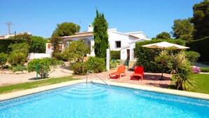 A swimming pool with two red lounge chairs and a white umbrella. - Belle Villa Avec Piscine 5 x 10 m, Grand Jardin Privatif, Proche des Plages (JAVEA)