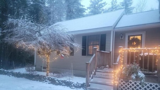 A house with a snow-covered porch, steps, and a fence.