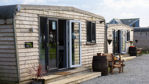 A wooden cabin with a sign indicating a parking area. - Wheal Amelia Lodge (Helston)