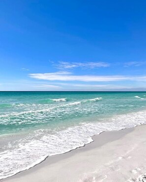 A beach with clear turquoise water and a wide sandy shore. - Golf Cart to Beach + Walk to Pool + Park 4 SUVs (Destin)