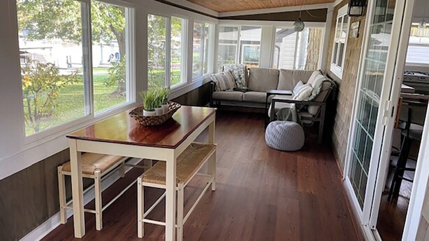 Una habitación soleada con una mesa de madera, un banco y un sofá con cojines.