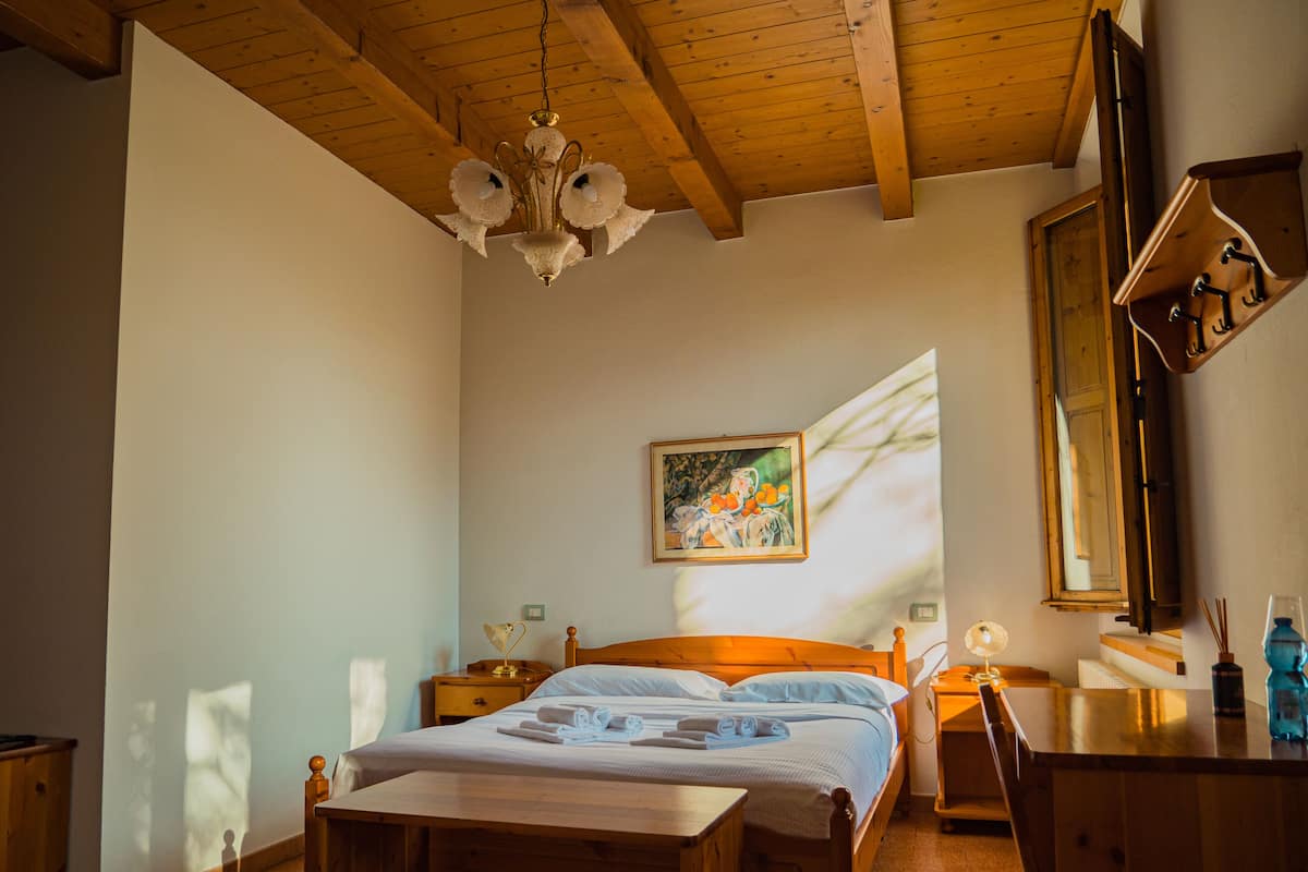 A bedroom with a wooden bed, a nightstand, a dresser, and a painting on the wall.