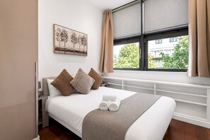 Ein Hotelzimmer mit Bett, einem Fenster mit Vorhängen, einem Heizkörper und einem Bild an der Wand.