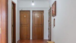 A hallway with two wooden doors, a small stool, and a wall-mounted cabinet. - Global Guest Sintra (Sintra)