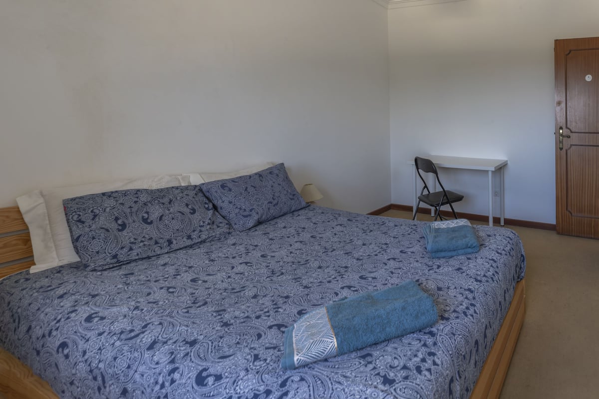 Quarto com cama, escrivaninha e guarda-roupa.