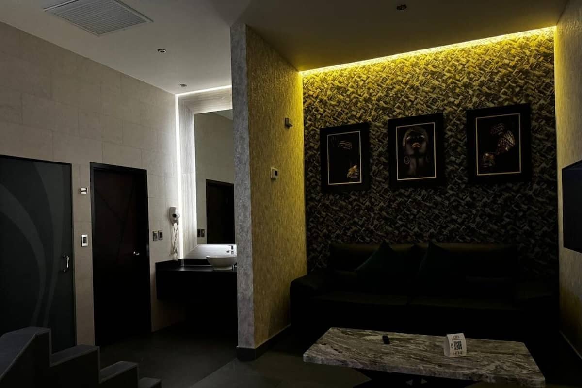 A modern hotel lobby with a reception desk, a sofa, and framed artwork on the wall.