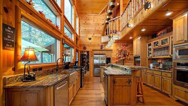 Una cocina amplia con armarios de madera, una isla grande y vistas al exterior a través de las ventanas.