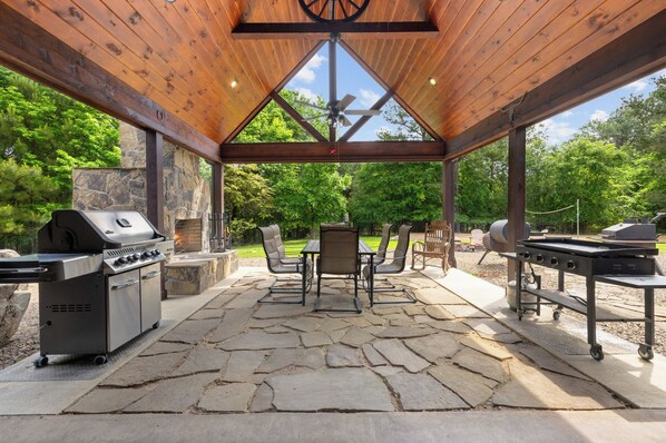 Enjoy al fresco dining and relaxation in this serene outdoor space with a stone fireplace, grill, and comfortable seating.