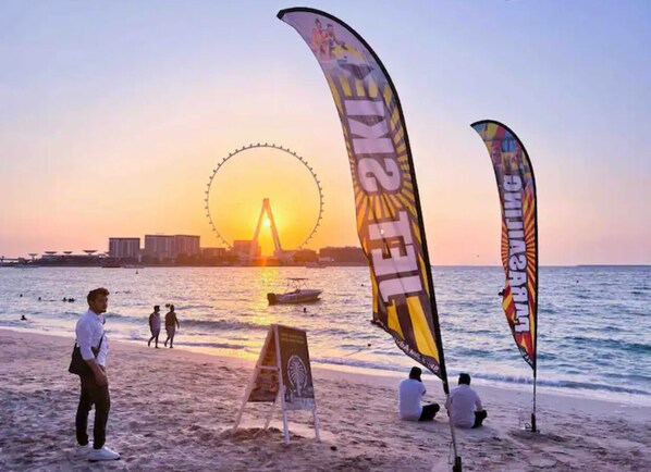 Enjoy a serene beach experience with access to the ocean, a Ferris wheel in the distance, and a lively atmosphere.