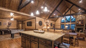 Una cocina amplia con una isla de granito, armarios de madera y una chimenea de piedra.