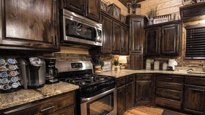 Una cocina con alacenas de madera oscura, una estufa de acero inoxidable, un microondas y una cafetera.