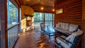 A wooden cabin interior with a stone fireplace, a sofa, and a dining table. - Fall in love with Legends Of The Fall cabin. Play Games & Soak in Large Hot Tub! (Broken Bow)