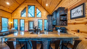 A spacious kitchen with a large island, bar stools, and wooden cabinetry. - Fall in love with Legends Of The Fall cabin. Play Games & Soak in Large Hot Tub! (Broken Bow)