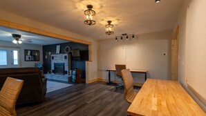 Amplia sala de estar con chimenea, piso de madera y zona de comedor con mesa y sillas de madera.