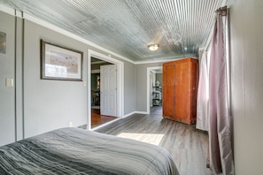 Un dormitorio con cama, un armario de madera y un pasillo que lleva a un baño.
