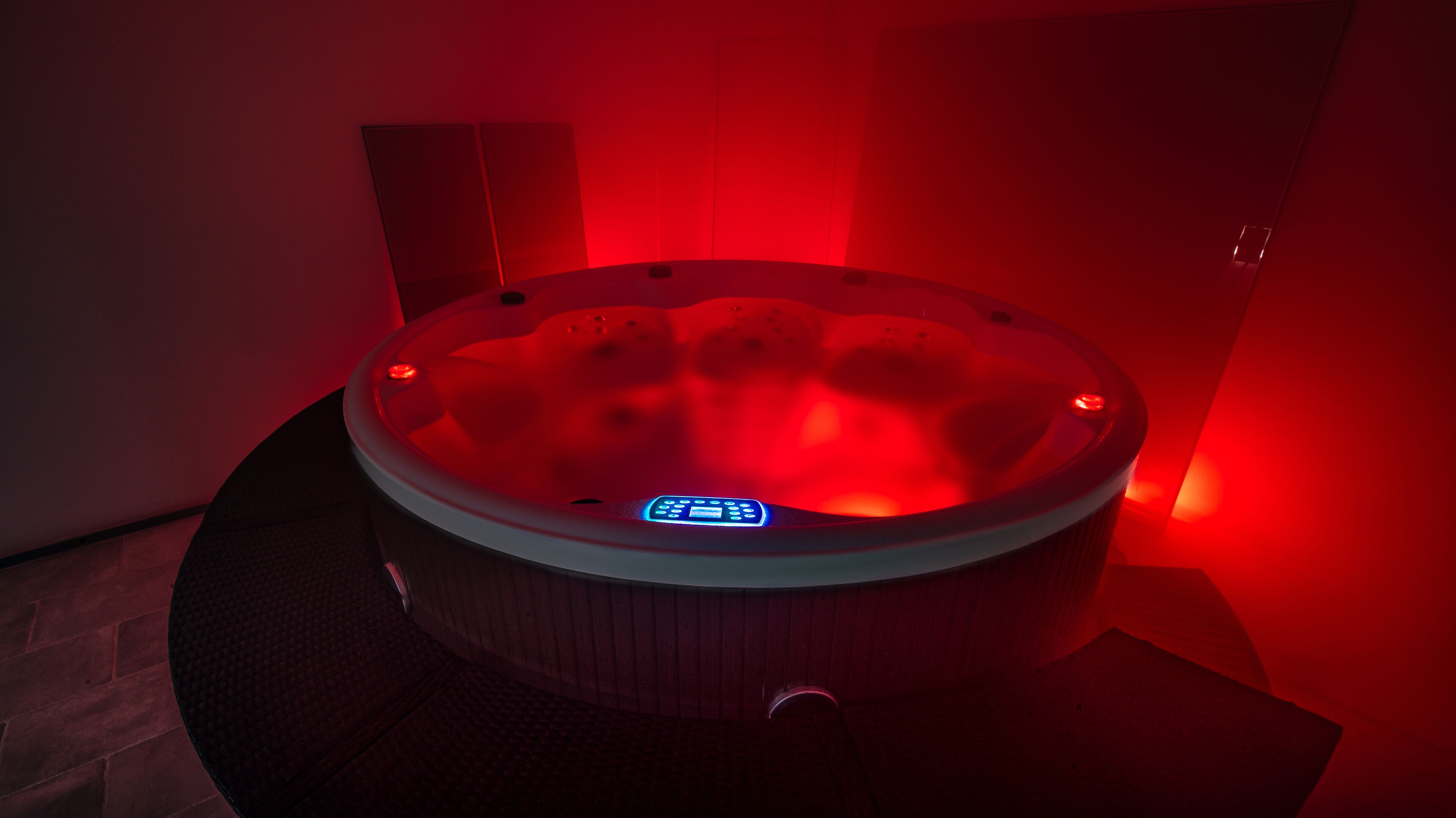 Een kuip met warm water en bedieningspaneel, omgeven door rode verlichting.