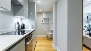 Une cuisine moderne avec une plaque de cuisson noire, des armoires blanches et un plancher en bois.