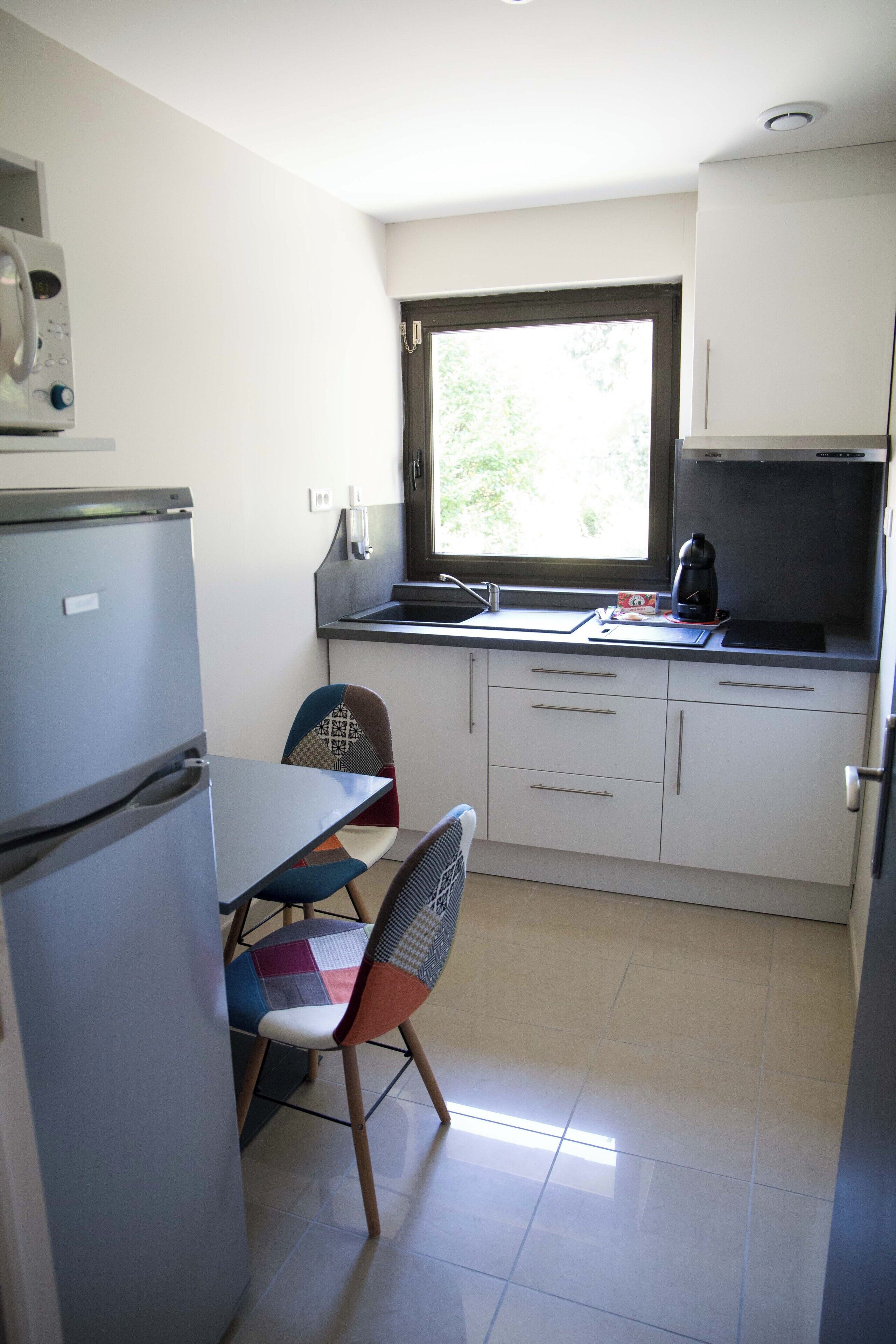Eine kleine Küche mit Kühlschrank, Spüle und Fenster.