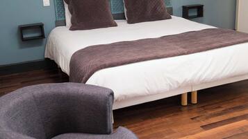 Un dormitorio moderno con una cama grande, dos mesitas de noche, una silla y suelo de madera.