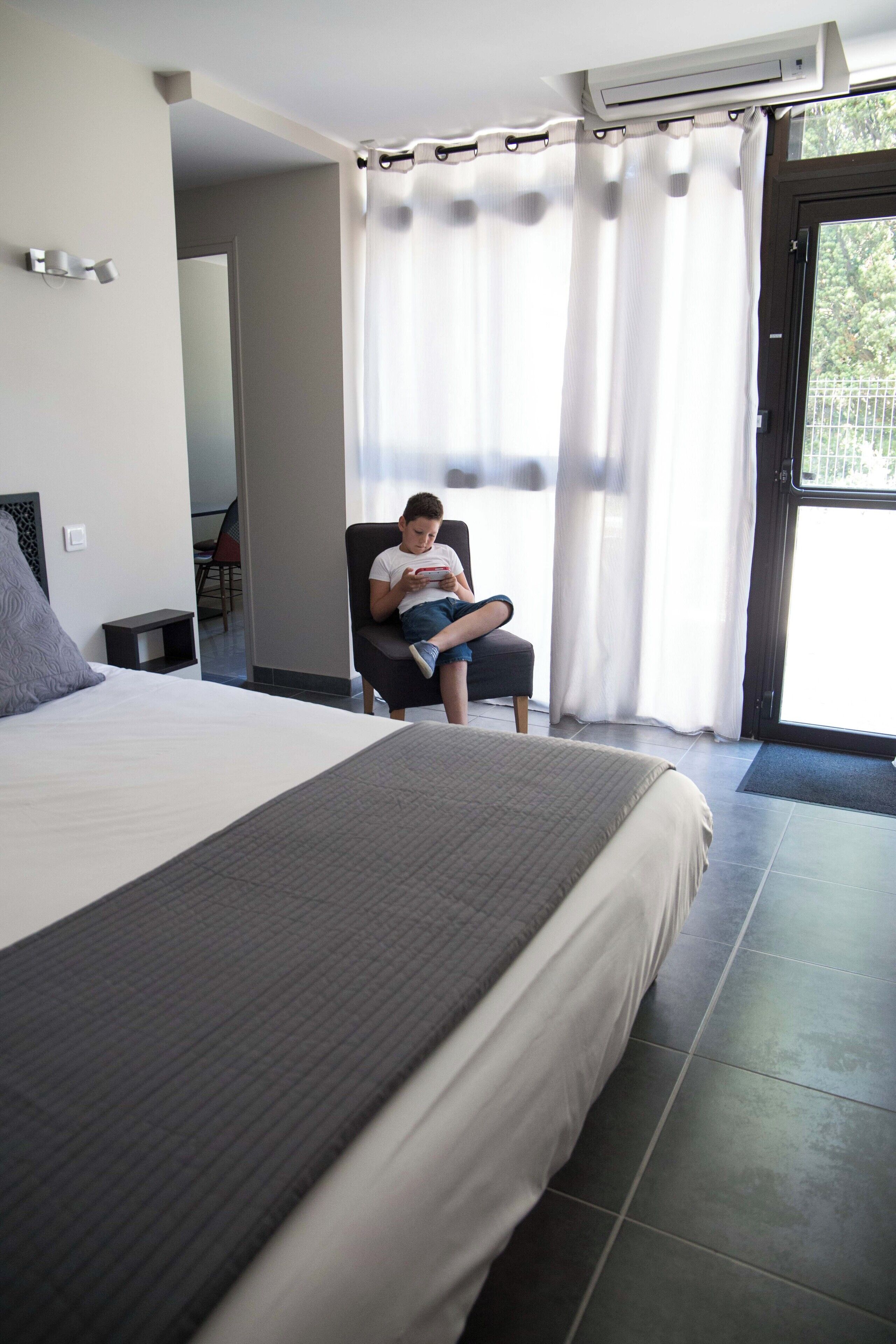 A hotel room with a large bed, a chair, and a window with curtains.