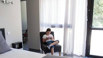 Une chambre d’hôtel avec un grand lit, une chaise et une fenêtre avec des rideaux.