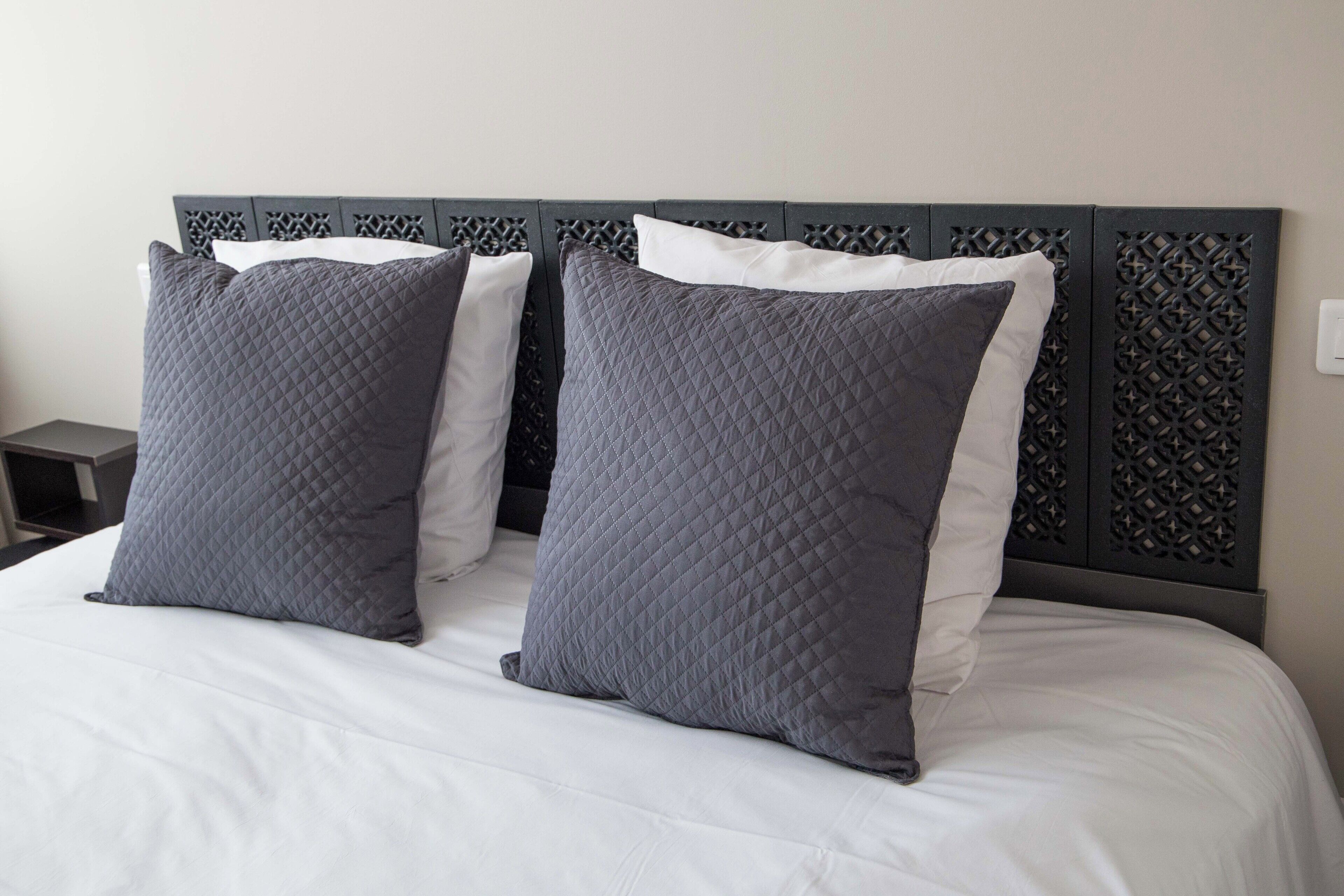 A bed with a quilted headboard and two pillows.